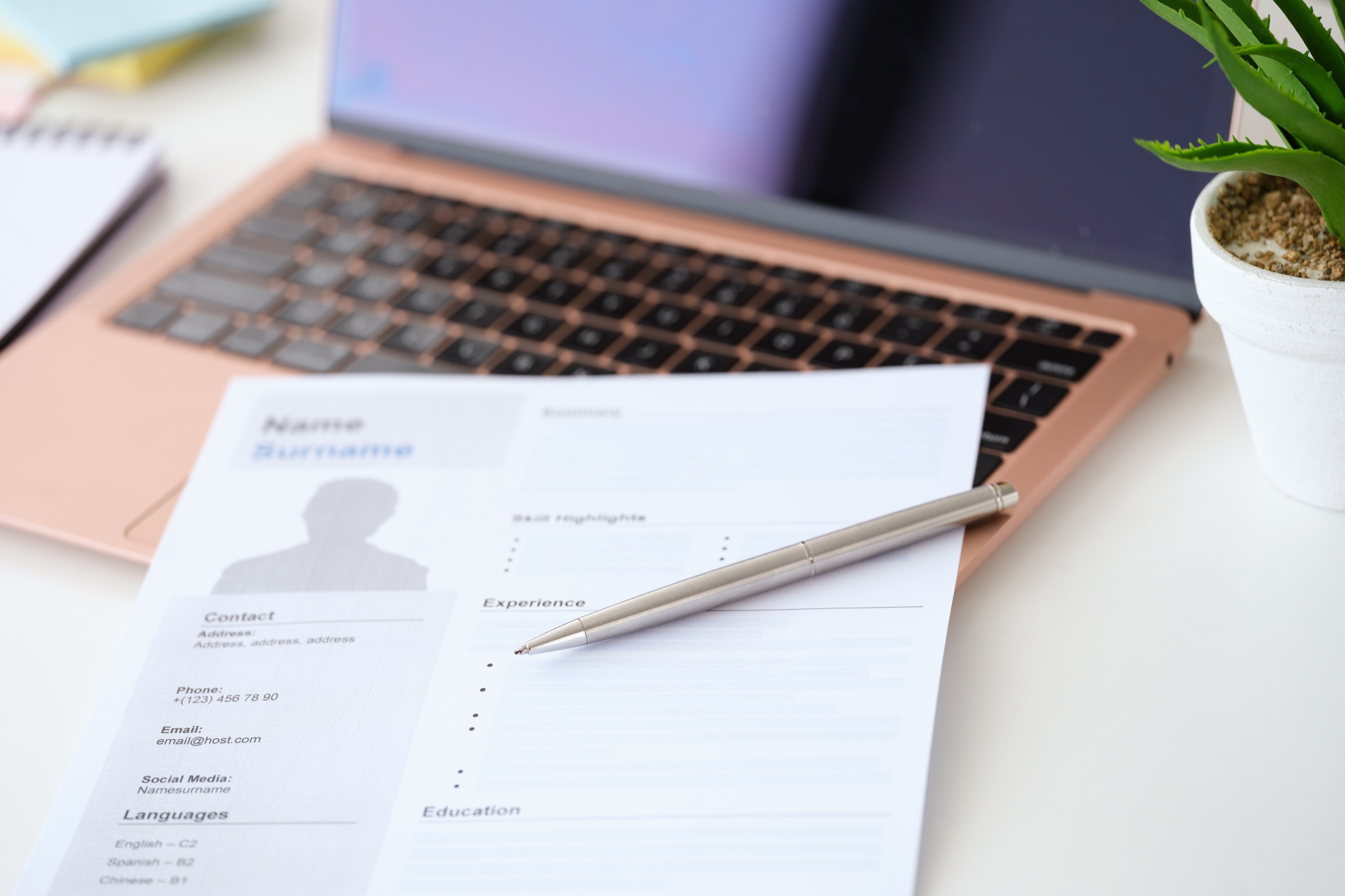 CV, długopis i laptop na biurku